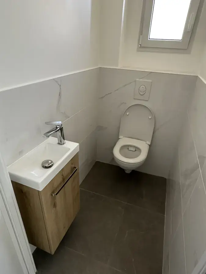 WC suspendu avec lave-mains sur meuble chêne, faïence effet marbre