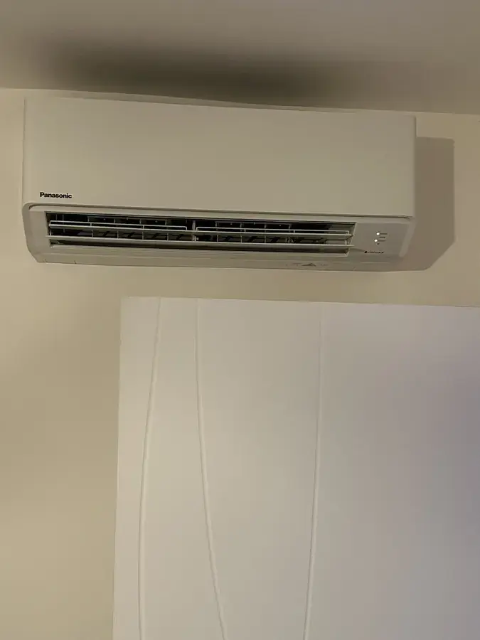 Unité intérieure de climatisation murale au-dessus d'une porte, finition blanche