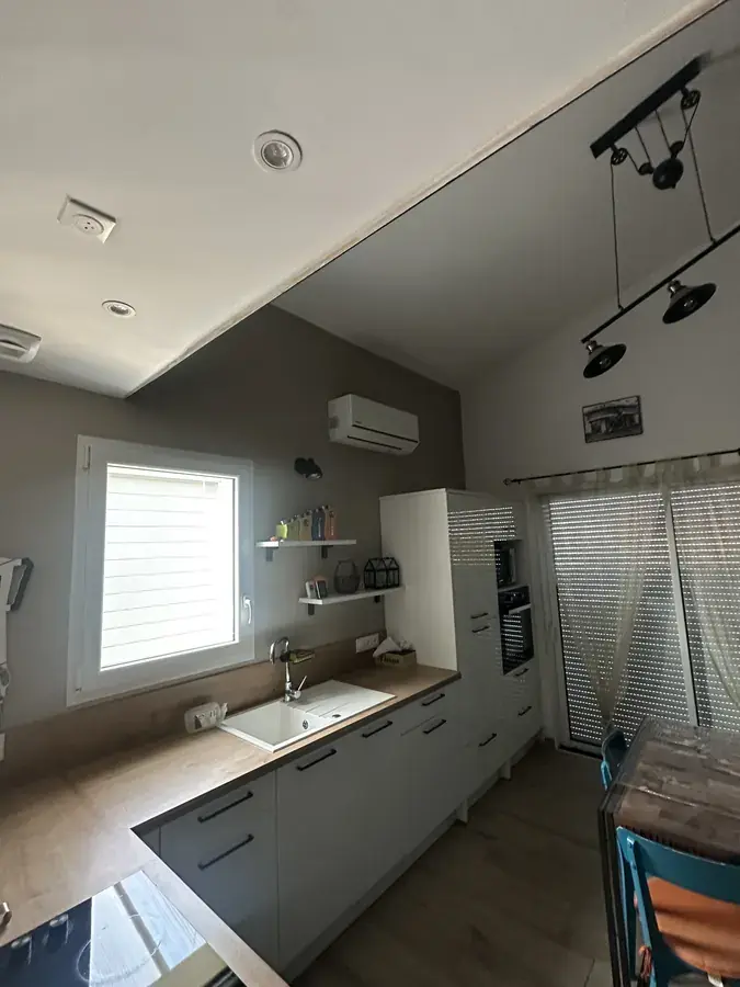 Cuisine ouverte sous rampant avec unité de climatisation murale installée en hauteur